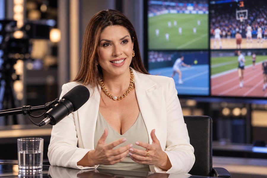Carina Batista em entrevista com monitores de diferentes modalidades esportivas ao fundo